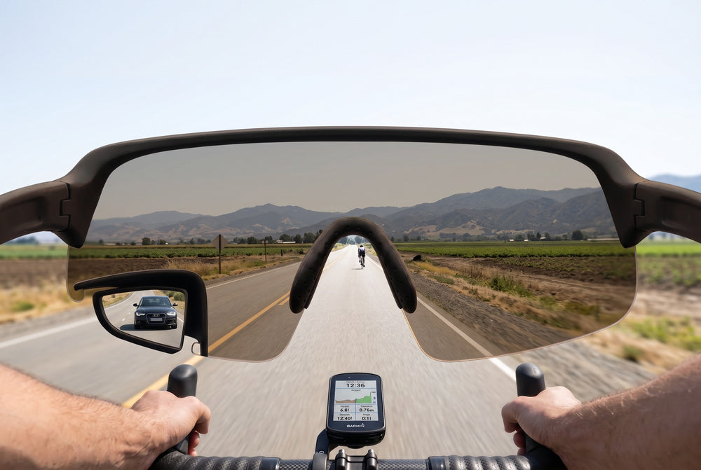 POV through TriEye eyewear on a road bike, portrait: the full width of the frame with a car visible in the built-in mirror at the lower left
